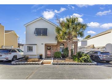 Charming two-story home with a red brick entryway, landscaped yard, and palm tree at 1004 Edge Dr., North Myrtle Beach, SC 29582