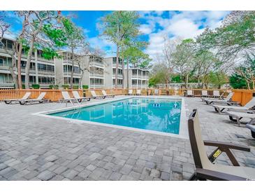 Community pool with lounge chairs and surrounding trees at 415 Ocean Creek Dr. # 2373, Myrtle Beach, SC 29572