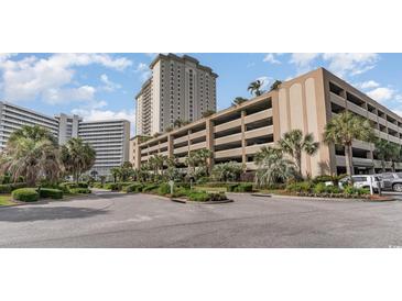 Exterior view of a high-rise condo building with parking garage and lush landscaping at 9994 Beach Club Dr. # 1604, Myrtle Beach, SC 29572