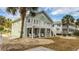 Two-story home with a deck and white chairs, near palm trees at 1906 S Ocean Blvd., North Myrtle Beach, SC 29582