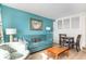 Living area with a blue sofa and matching armchair, small dining table, and beach artwork at 4800 S Ocean Blvd. # 615, North Myrtle Beach, SC 29582