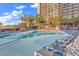 Resort pool with lounge chairs, palm trees, and a tall building in the background at 4800 S Ocean Blvd. # 615, North Myrtle Beach, SC 29582