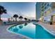 Resort-style pool with palm trees and lounge chairs at sunset at 2711 S Ocean Blvd. S # 1421, North Myrtle Beach, SC 29582