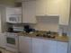 Kitchen with white cabinets, granite counters, and appliances at 14290 Ocean Hwy. # 103, Pawleys Island, SC 29585