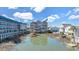 Three-story waterfront home with a wooden dock, surrounded by other houses and marsh at 206 60Th Ave. N # 203, North Myrtle Beach, SC 29582