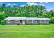 Gray house with metal roof, large green lawn, and a tree line in the background at 4612 Red Bluff Rd., Loris, SC 29569