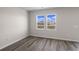 Well-lit bedroom featuring wood-look floors and two windows at 3058 Deerberry Place, Longs, SC 29568