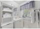 Clean bathroom with white vanity, shelving, and a window with gray curtains at 605 36Th Ave. S, North Myrtle Beach, SC 29582