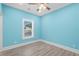 Light blue bedroom with wood-look floors, ceiling fan, and window with blinds at 6001-N37 S Kings Hwy., Myrtle Beach, SC 29575