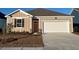Beige house with orange door, two-car garage, and landscaped yard at 580 Duvall St., Longs, SC 29568