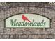 Meadowlands community entrance sign with brick border and cardinal at 794 Thistle Trail, Calabash, NC 28467