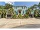 Attractive two-story home with a light teal exterior, lush landscaping, and a circular driveway at 119 Cockle Shell Ct., Pawleys Island, SC 29585