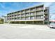Exterior view of the multi-story building with ample parking at 120 North Dogwood Dr. # 113, Garden City Beach, SC 29576