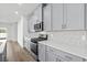 Modern kitchen features gray cabinets, stainless steel appliances, and hexagon backsplash at 801 Cypress Preserve Circle, Longs, SC 29568