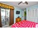 Bedroom with a red snowflake comforter, ceiling fan, and access to balcony at 4305 S Ocean Blvd. # 205, North Myrtle Beach, SC 29582