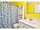Bright yellow bathroom with white vanity and shower at 4305 S Ocean Blvd. # 205, North Myrtle Beach, SC 29582