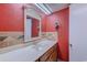 Bathroom with wood vanity, red walls, and a framed mirror at 1501 S Ocean Blvd. # 1038, Myrtle Beach, SC 29577