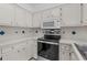 Well-lit kitchen with white cabinets, stainless steel appliances, and tile countertops at 2925 Carriage Row Ln. # 134, Myrtle Beach, SC 29577