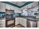 Kitchen with white cabinets, black appliances, and teal walls at 814 N Waccamaw Dr. # 311, Garden City Beach, SC 29576