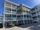 Three-story building with light blue exterior, balconies, and a palm tree in front at 700 N Waccamaw Dr. # 319, Garden City Beach, SC 29576