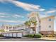 Exterior view of a peach-colored building with brick accents and garages at 4878 Dahlia Ct. # 24-304, Myrtle Beach, SC 29577