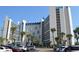 Exterior view of a multi-story building with palm trees and parking at 7100 Ocean Blvd. N # 825, Myrtle Beach, SC 29572