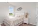 Bedroom with white bed and striped comforter, featuring a window with natural light at 522 Firouz Dr, Longs, SC 29568