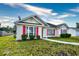 House exterior featuring a beige vinyl-sided home with red shutters and landscaping at 4336 Summitt Trail, Myrtle Beach, SC 29579