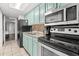 Efficient galley kitchen with teal cabinets, stainless steel appliances, and tile backsplash at 6804 Ocean Blvd. # 331, Myrtle Beach, SC 29572