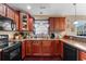 L-shaped kitchen with dark wood cabinets, black appliances, and double sink at 818 Ingle Nook Ln., Longs, SC 29568