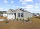 View of a green-sided house with a white garage door and neatly landscaped yard at 1143 Sennema Circle, Myrtle Beach, SC 29588