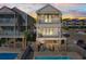 Rear exterior view of beach house with pool, patio, and sunset view at 411A Ocean Blvd. S, Surfside Beach, SC 29575