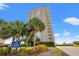 View of high-rise condo with lush landscaping and signage at 9820 Queensway Blvd. # 903, Myrtle Beach, SC 29572
