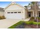 Beige house with white garage door, landscaping, and palm trees at 1276 Marsilio Ln Sw, Ocean Isle Beach, NC 28469