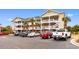 Three-story condo building with ample parking and palm trees at 5801 Oyster Catcher Dr. # 324, North Myrtle Beach, SC 29582