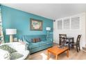 Living area with a blue sofa and matching armchair, small dining table, and beach artwork at 4800 S Ocean Blvd. # 615, North Myrtle Beach, SC 29582