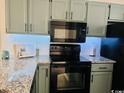 Kitchen with light green cabinets, granite counters, and black appliances at 1840 Fairway Ridge Dr. # 8-F, Surfside Beach, SC 29575