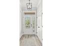 Modern entryway with a large white door, wood floors and a chandelier at 16 Mullet Bay Rd, Pawleys Island, SC 29585