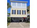 Two-story beach house with a yellow exterior, white trim, and black shutters at 5226 Highway 17 Business, Murrells Inlet, SC 29576