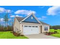 Tan house with blue accents, white garage door, and landscaped lawn at 512 Sheepbridge Way, Loris, SC 29569