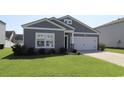 Gray exterior of charming one-story house with white garage door and manicured lawn at 163 Marsh Deer Place, Surfside Beach, SC 29575