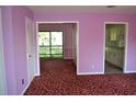 Living room with purple walls, red carpet, and access to kitchen and patio at 2000 Greens Blvd. # 18-D, Myrtle Beach, SC 29577