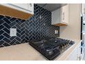Close-up view of a gas cooktop with dark herringbone tile backsplash at Tbb1 Shady Grove Rd., Conway, SC 29527