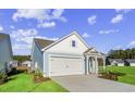 Light blue house with white accents and a two-car garage. Landscaped lawn at 3022 Deerberry Place, Longs, SC 29568