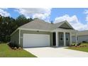 Single-story house with gray siding, white garage door, and a landscaped yard at 301 Cheerful Way, Little River, SC 29566