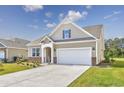 Two-story house with a beige exterior, a white garage door, and landscaping at 6041 Mcclain Ct., Little River, SC 29566