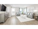 Bright living room features stylish furniture, light hardwood floors, and large windows at 2748 Rowyn St., Longs, SC 29568
