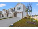 Row of townhomes with gray and white siding, two-car garages, and a palm tree at 237 Sandridgebury Dr. # 58, Little River, SC 29566