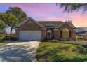 Brick home with landscaped yard and attached two-car garage at dusk at 44 Hamby Dr., Pawleys Island, SC 29585