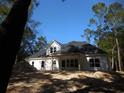Rear view of a white farmhouse nestled in a wooded lot at 681 Hawthorn Dr., Pawleys Island, SC 29585